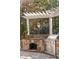 Outdoor kitchen boasts a built-in grill, a stone oven, a wood trellis, and overhead lights at 2480 Flint Creek Dr, Cumming, GA 30041