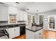 Bright kitchen features white cabinets, a black appliance package, and a center island with a gray granite top at 1605 Loblolly Ln, Cumming, GA 30041