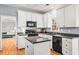 A bright kitchen with white cabinets, stainless steel appliances, granite counters, and a functional island at 1605 Loblolly Ln, Cumming, GA 30041