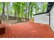 A spacious backyard deck with red painted wood is surrounded by a lush green forest at 3900 Millwood Lane Nw, Lilburn, GA 30047