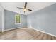 Bedroom with light hardwood floors, ceiling fan, and a large window with natural light at 3900 Millwood Lane Nw, Lilburn, GA 30047