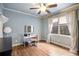 Light blue bedroom with hardwood floors, fan, and desk next to large window at 9369 Kraft Dr, Winston, GA 30187