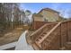 View of the home's back exterior, deck, stairs, walkway, and wooded backyard with a wooden fence at 1554 Sage Ridge Dr, Marietta, GA 30064