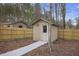 Tan storage shed in the backyard, complete with a walkway, bare trees, and a wood fence at 1554 Sage Ridge Dr, Marietta, GA 30064