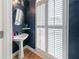 Stylish powder room with a pedestal sink, round mirror, and plantation shutters for added privacy at 2426 Vivian Cir, Decatur, GA 30030