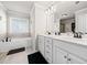 Bathroom featuring double sinks, white cabinets, and a luxurious soaking tub at 3865 Brookhollow Dr, Douglasville, GA 30135