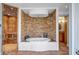 Luxurious bathroom featuring a soaking tub and stone accent wall, along with a glass-enclosed shower at 3460 Mansions Pkwy, Berkeley Lake, GA 30096