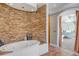 Elegant bathroom with a standalone tub and stone accent wall, creating a spa-like ambiance for relaxation and rejuvenation at 3460 Mansions Pkwy, Berkeley Lake, GA 30096