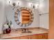 Stylish bathroom vanity with a round, decorative mirror and granite countertop at 3460 Mansions Pkwy, Berkeley Lake, GA 30096