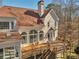 Large back exterior of home with sunroom, wooden deck, and wooded backyard at 3460 Mansions Pkwy, Berkeley Lake, GA 30096