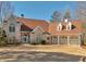 A charming two-story home has a manicured lawn, arched windows, and a three-car garage at 3460 Mansions Pkwy, Berkeley Lake, GA 30096