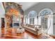 Cozy living room with fireplace, hardwood floors, large arched windows, and comfortable seating at 3460 Mansions Pkwy, Berkeley Lake, GA 30096