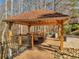 Charming gazebo encasing an outdoor kitchen area with a stainless steel grill, dining table, and stone accents in a serene setting at 3460 Mansions Pkwy, Berkeley Lake, GA 30096