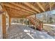 A covered patio area with wooden beams, steps, and views of the surrounding woods at 3460 Mansions Pkwy, Berkeley Lake, GA 30096