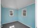 Small, brightly lit room with light blue walls, grey carpet, white trim, and two windows overlooking trees at 3460 Mansions Pkwy, Berkeley Lake, GA 30096