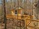 Quaint treehouse with a deck, accessible by a wooden walkway in a wooded setting at 3460 Mansions Pkwy, Berkeley Lake, GA 30096