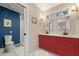 Bathroom featuring dual sinks, white countertops, a red vanity, toilet and glass shower at 633 Mckoy St, Decatur, GA 30030