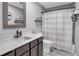 Well-lit bathroom featuring modern fixtures, gray tile flooring and shower with neutral striped shower curtain at 6890 Cedar Mountain Rd, Douglasville, GA 30134