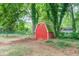 View of a red barn in a grassy backyard with mature trees and lush greenery at 411 Burke Cir, Mcdonough, GA 30253