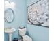 Charming powder room featuring blue walls, pedestal sink, oval mirror, and floral artwork at 640 Blackshear Trl, Temple, GA 30179