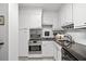 Well-lit kitchen featuring white cabinetry, modern appliances, granite countertops, and tile backsplash at 2965 Pharr Court South Nw # 712, Atlanta, GA 30305