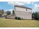 View of the grassy backyard, white brick exterior and wooden deck with stairs at 11760 Stratham Dr, Alpharetta, GA 30009