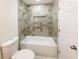 Bathroom with tub-shower, tiled walls, toilet, and marble-tiled floor in the bath area at 2192 Stenger Rd, Douglasville, GA 30135