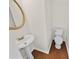 Small bathroom featuring a pedestal sink with a gold mirror and a toilet on wood floors at 380 Birchmere Sw, Atlanta, GA 30331