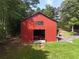 View of a spacious red barn with a tractor inside, located on a grassy lot at 4079 Bullock Bridge Rd, Loganville, GA 30052