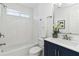 A bathroom featuring a navy vanity, subway tiled shower, and a white ceramic tile floor at 2395 Saint James Nw Dr, Atlanta, GA 30318