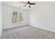 A well-lit bedroom with a ceiling fan, soft gray carpet, and a view of the backyard at 2395 Saint James Nw Dr, Atlanta, GA 30318