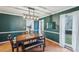 Dining room with dark green walls, wooden table, bench, and modern light fixture at 381 Gates Mil Dr, Lawrenceville, GA 30045