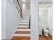 Staircase with wood steps, white risers, and a black handrail, located near a half bathroom at 381 Gates Mil Dr, Lawrenceville, GA 30045