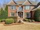 Close up of classic red brick home featuring a covered front porch with meticulously trimmed hedges and lawn at 1320 Kildare Ct, Snellville, GA 30078