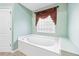 Bathroom with a soaking tub, a window with decorative drapery, and a separate shower area at 1119 Simonton Glen Way, Lawrenceville, GA 30045