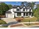 New construction home featuring white siding, black trim, a covered porch, and a two-car garage at 320 Dodd Ln, Alpharetta, GA 30005