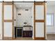 Stylish wet bar with subway tile backsplash, stainless steel sink, beverage fridge, and rustic barn doors at 560 John Wesley Dobbs Ave, Atlanta, GA 30312
