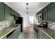 Well-lit kitchen with sleek appliances, dark green cabinets, granite countertops, and a stylish tile backsplash at 2107 Seavey Dr, Decatur, GA 30032