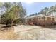 Backyard featuring brick home exterior, patio, and a lawn surrounded by mature trees at 3435 Macland Rd, Powder Springs, GA 30127