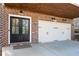 A double door garage is made with brick and painted white doors with black accents at 140 Rigby Ne St, Marietta, GA 30060