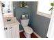 Powder room with gray walls, pedestal sink, toilet, wood floors, and decorative plants on a shelf and on the toilet at 4845 Dartford Dr, Powder Springs, GA 30127