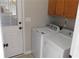 Laundry room with white washer and dryer next to a door leading outside and wooden cabinets mounted on the wall at 4845 Dartford Dr, Powder Springs, GA 30127