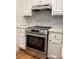 The kitchen has a stainless steel oven, white cabinets and grey mosaic tile backsplash at 5531 Four Winds Sw Dr, Lilburn, GA 30047