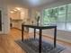 Bright kitchen with white cabinets, stone backsplash, and hardwood floors, dining area with large windows overlooking a wooded view at 5531 Four Winds Sw Dr, Lilburn, GA 30047