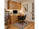 Bright office space with built-in wooden desk, drawers and shelving, with light wood floors, grey chair and art at 5531 Four Winds Sw Dr, Lilburn, GA 30047