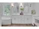 Bright white bathroom featuring a double vanity, soaking tub, shutters, and wood-look tile floors at 2599 Oglethorpe Ne Cir, Brookhaven, GA 30319