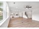 Open-concept living room with hardwood floors, large windows, and a view of the modern kitchen and staircase at 1356 Auburn Glen Rd, Dacula, GA 30019