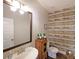 A stylish half-bathroom featuring a rustic vanity, weathered wood accent wall, and dark laminate flooring at 207 Tan Yard Rd, Social Circle, GA 30025
