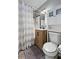 This well-lit bathroom offers a toilet, a wood-paneled sink cabinet, and a shower-tub behind a striped shower curtain at 4558 Ryan Rd, Conley, GA 30288