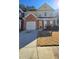 Two-story townhome featuring a brick and yellow exterior, attached garage, and lawn at 553 Rockbridge Trl, Stone Mountain, GA 30083